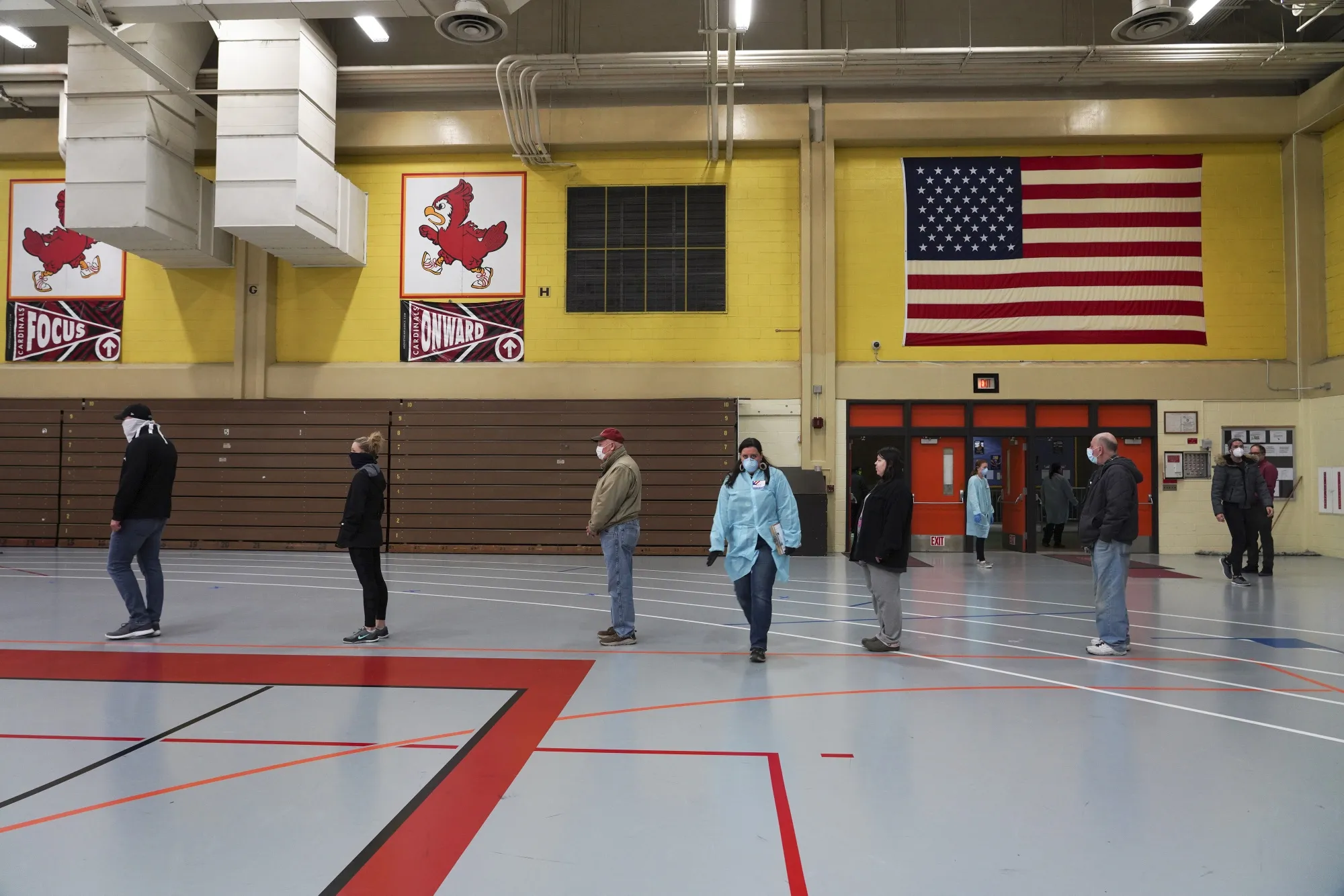 Voters wearing protective masks stand in line to cast ballots at a polling station in Milwaukee on April 7.