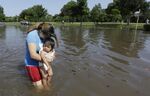 Gabby Aviles carries her daughter Audrey through floodwaters outside their apartment in Houston on Tuesday, May 26, 2015.