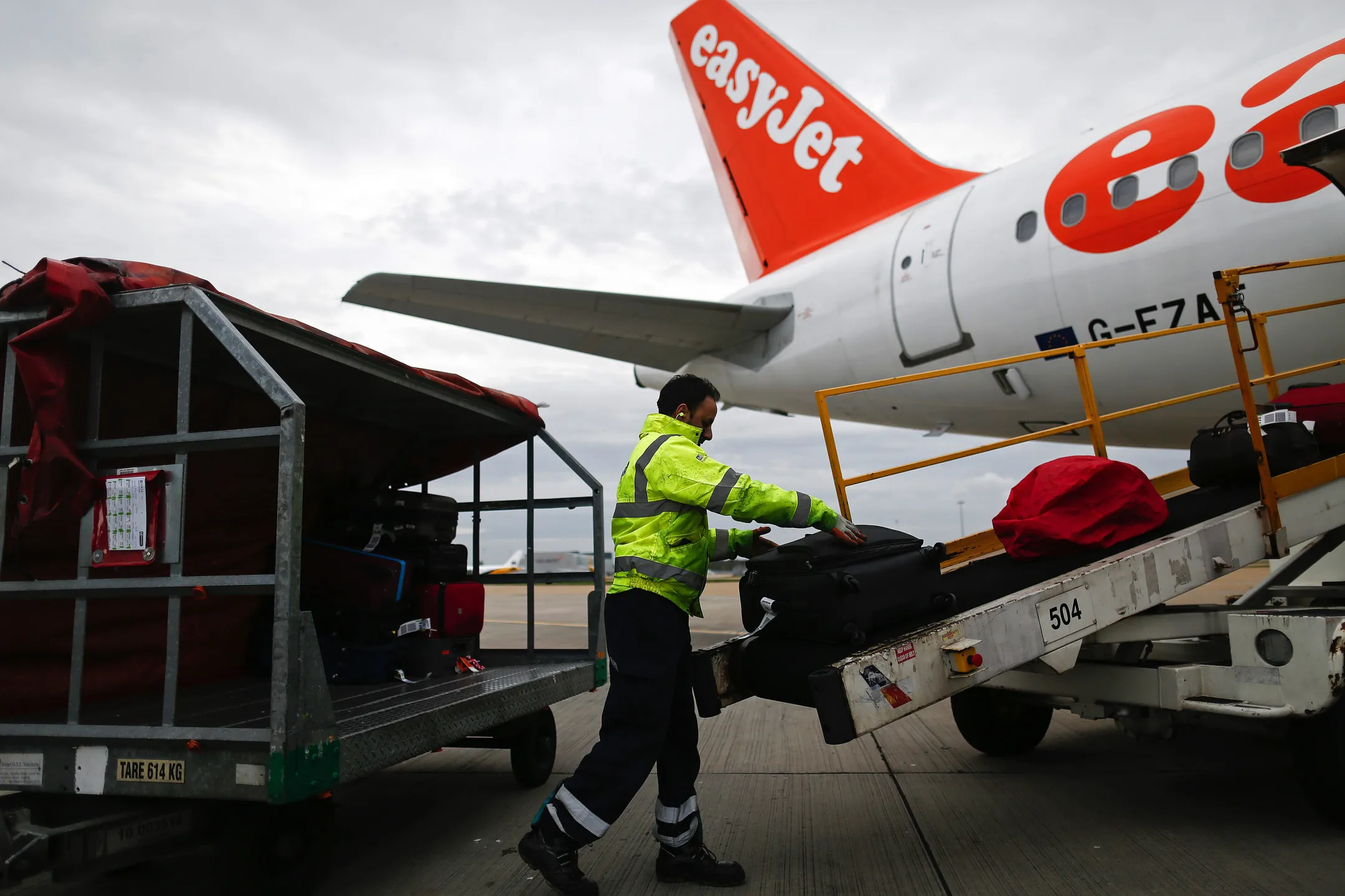 A baggage handler loads&nbsp;passenger&nbsp;suitcases onto an aircraft at London Gatwick airport in Crawley, UK.