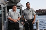 Officers Stephen Merrick, left, and Garrett Boyle, right, speak at a press conference at the Boston Harbor Patrol dock after rescuing two people aboard a sinking boat.