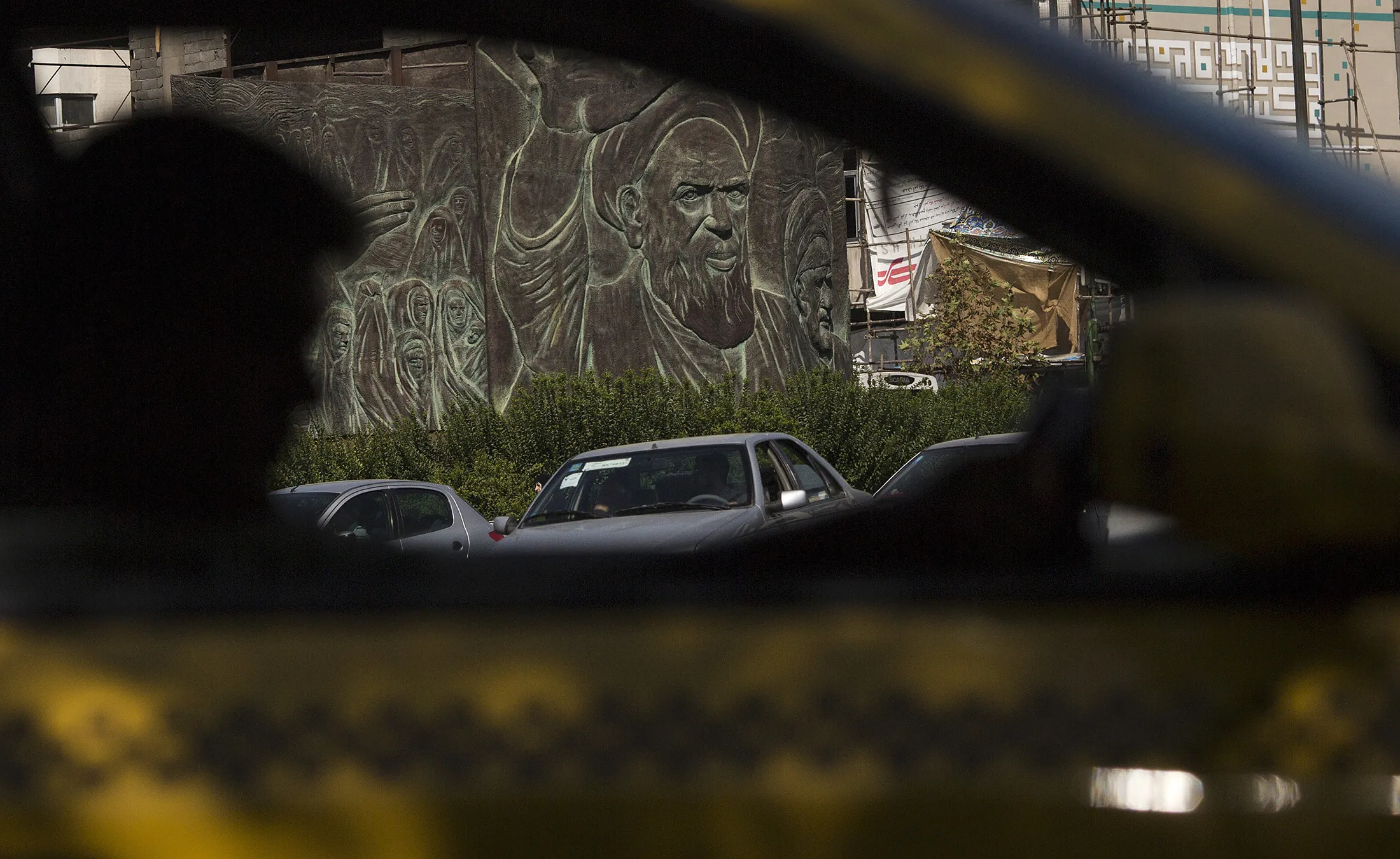 A yellow taxi cab passes a public monument showing the face of Ruhollah Khomeini, founder of the Islamic republic of Iran, in Tehran, on Aug. 31, 2015.
