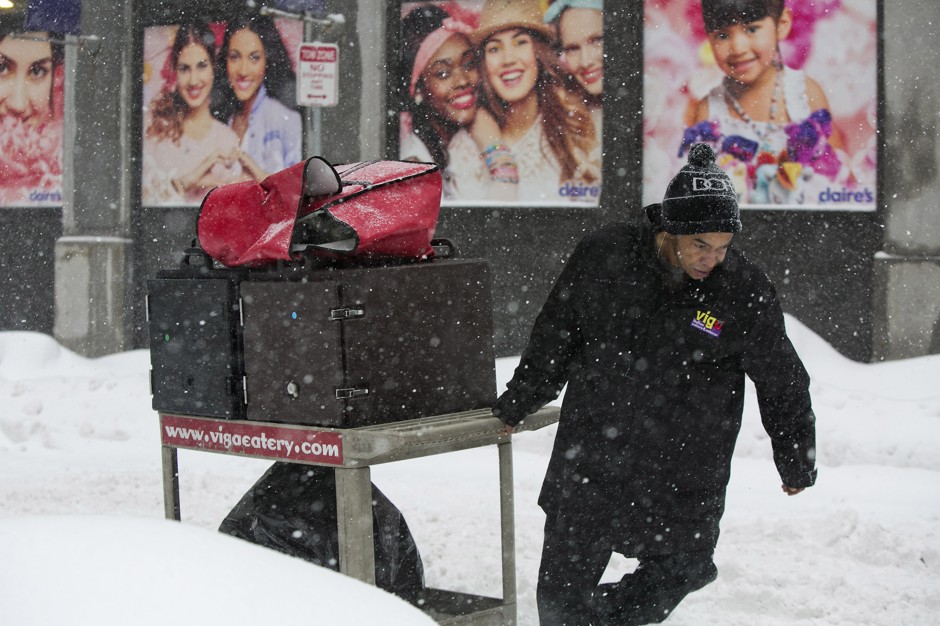 A food delivery worker pulls a cart up Milk Street during a snowstorm in Boston, Massachusetts on February 2, 2015. 