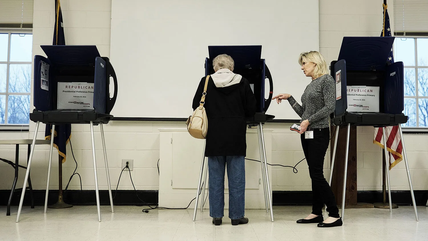 A poll volunteer helps a resident with a polling machine during the South Carolina Republican presidential primary election in Laurens, South Carolina, on Feb. 20, 2016.
