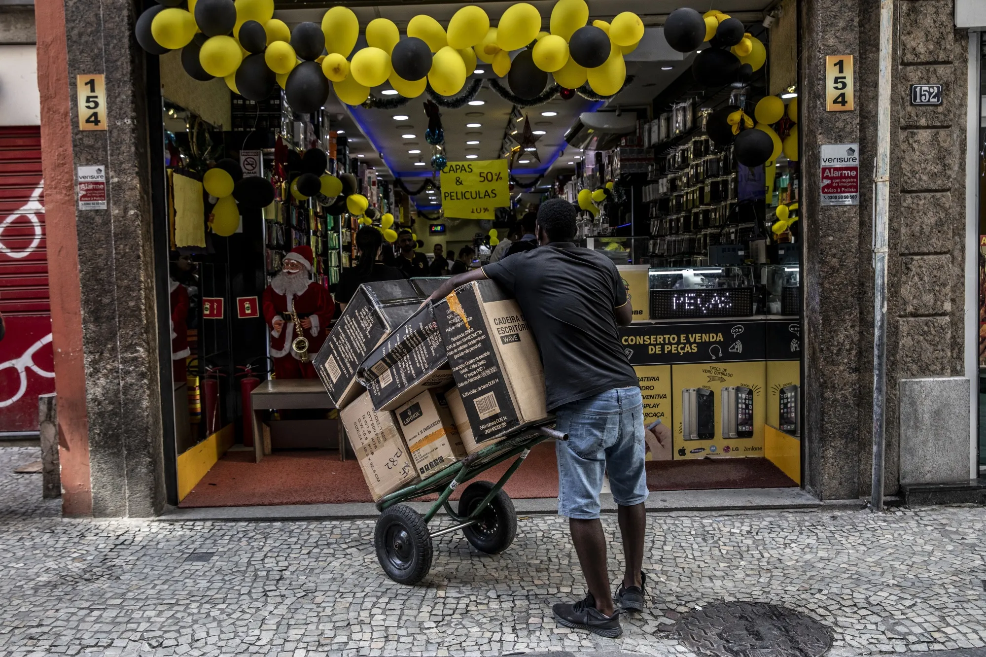 A worker holds a cart of products in front of a store&nbsp;in Rio de Janeiro, Brazil.