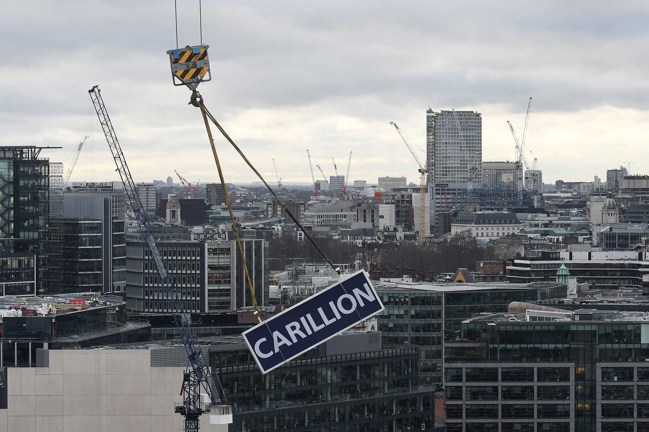 A sign with the name of liquidated British company Carillion is lowered after being taken down from a construction crane on a building site in the City of London on Jan. 23, 2018.