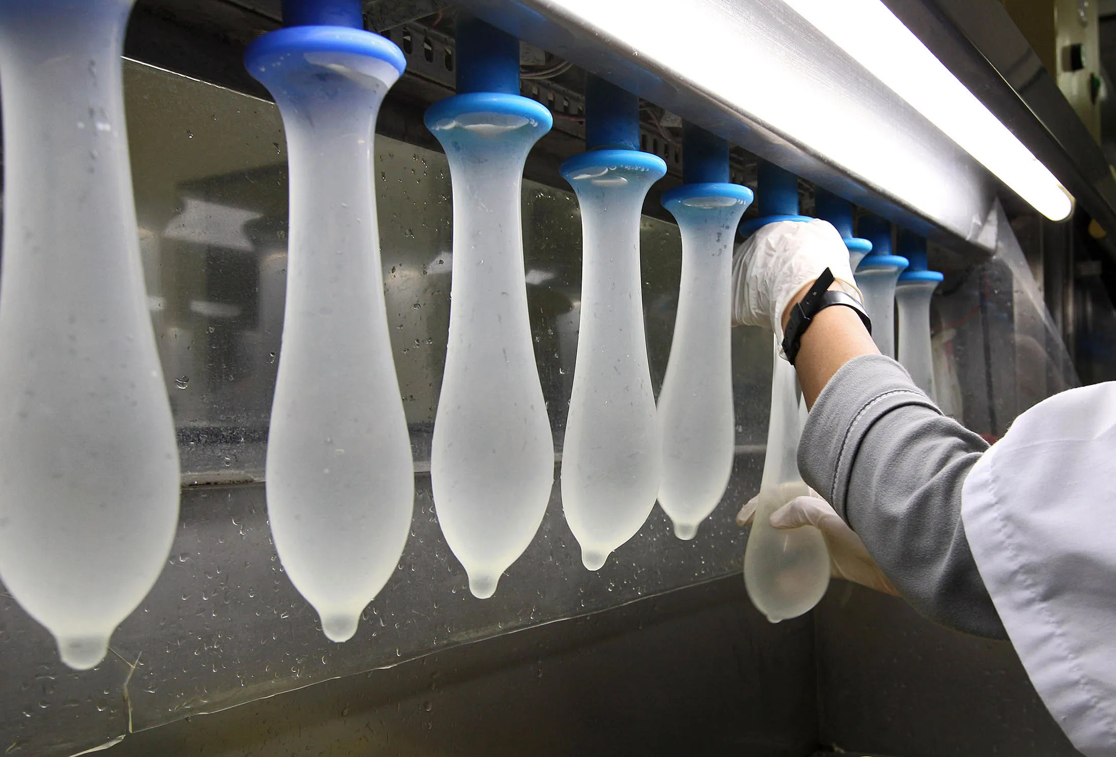 An employee inspects condoms during testing at a condom factory in Johor, Malaysia.
