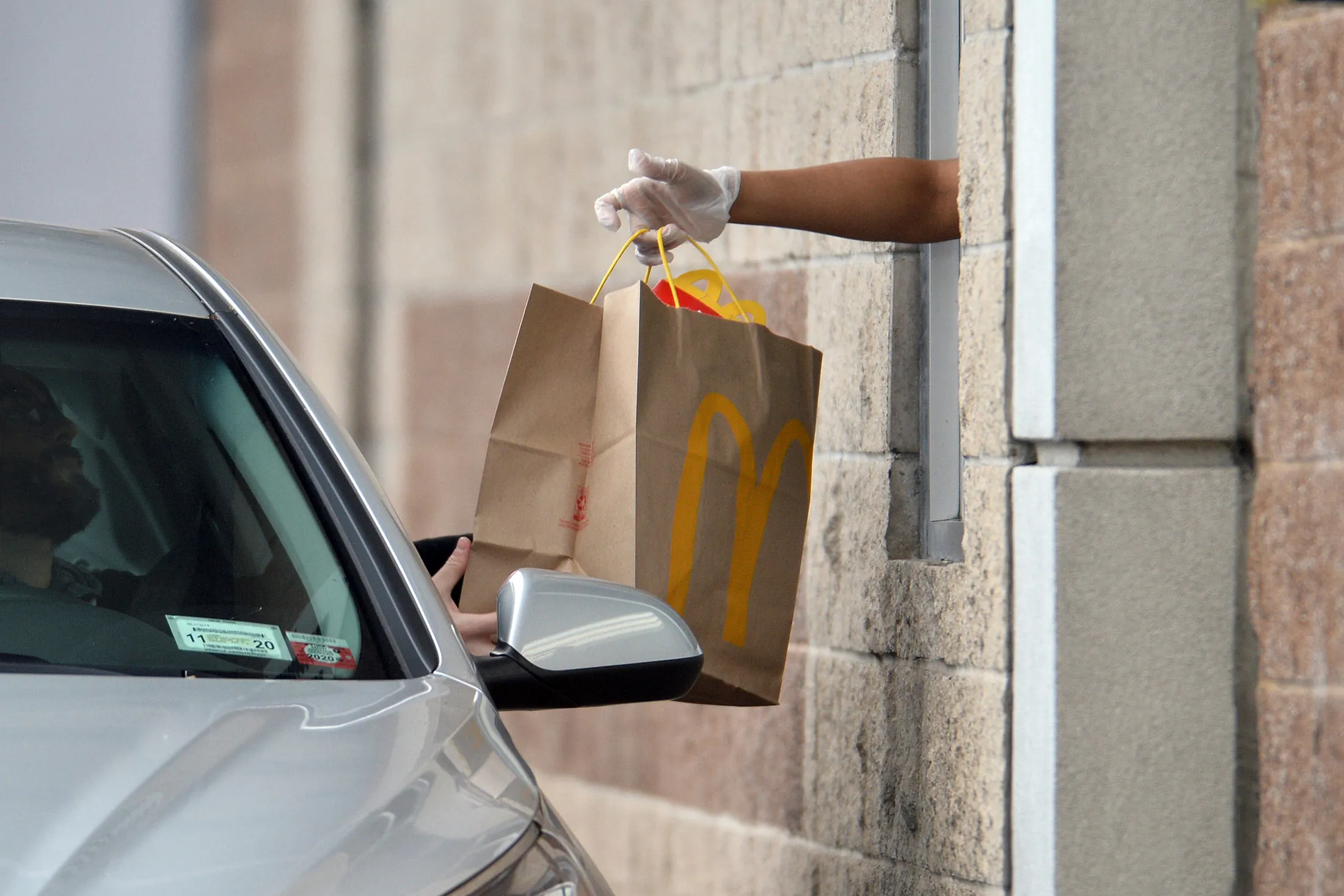 An employee wearing protective gloves hands a customer a take-out order at a McDonald’s drive-through in Queens, New York.