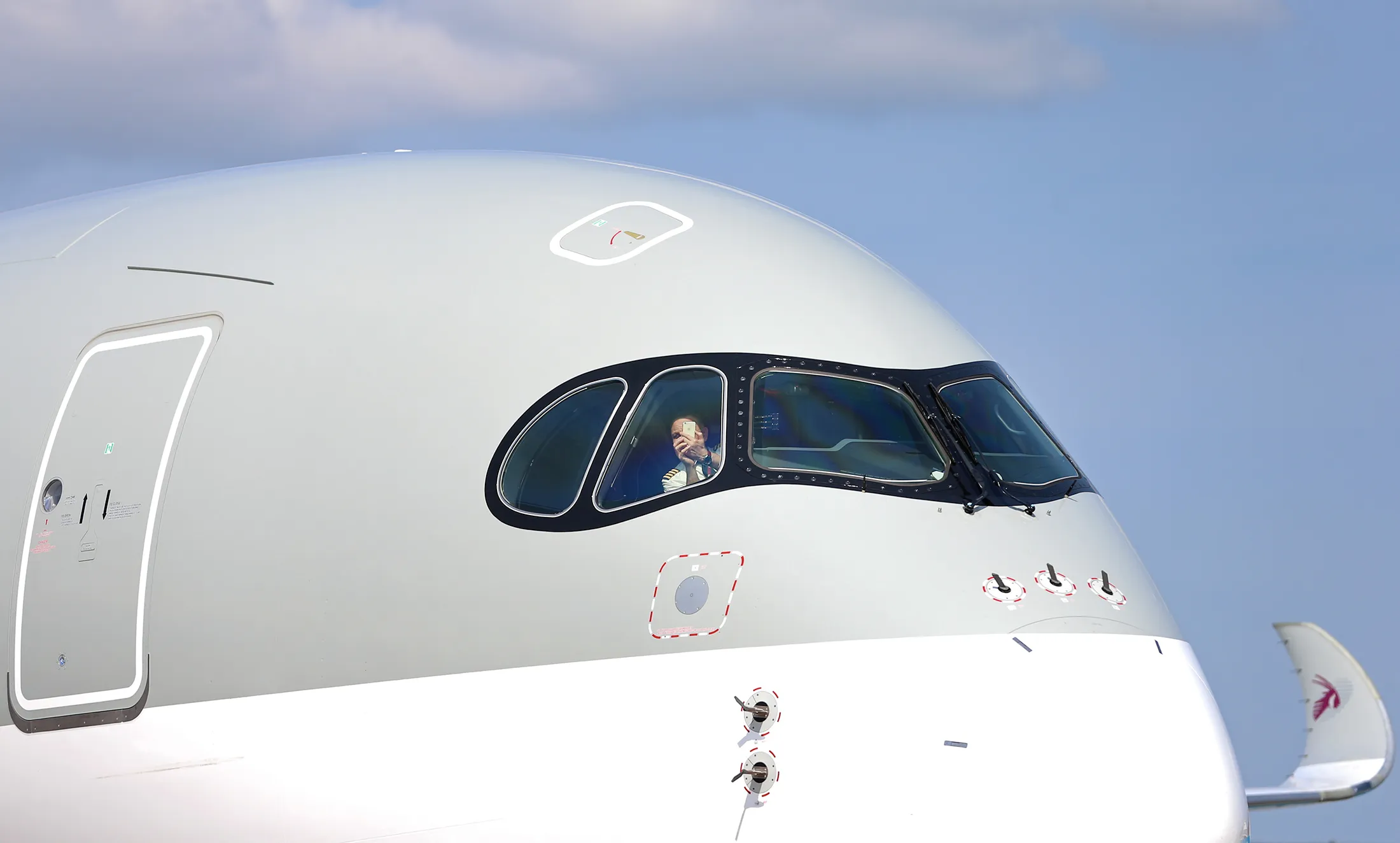 A pilot uses a smartphone to take a photograph from the cockpit of an Airbus A350 aircraft, operated by Qatar Airways Ltd., as it is manoeuvred into position after landing during preparations ahead of opening at the 51st International Paris Air Show in Paris, on June 14.
