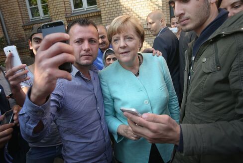 German Chancellor Angela Merkel pauses for a selfie with a migrant before she visited the AWO Refugium Askanierring shelter for migrants on September 10, 2015 in Berlin, Germany.