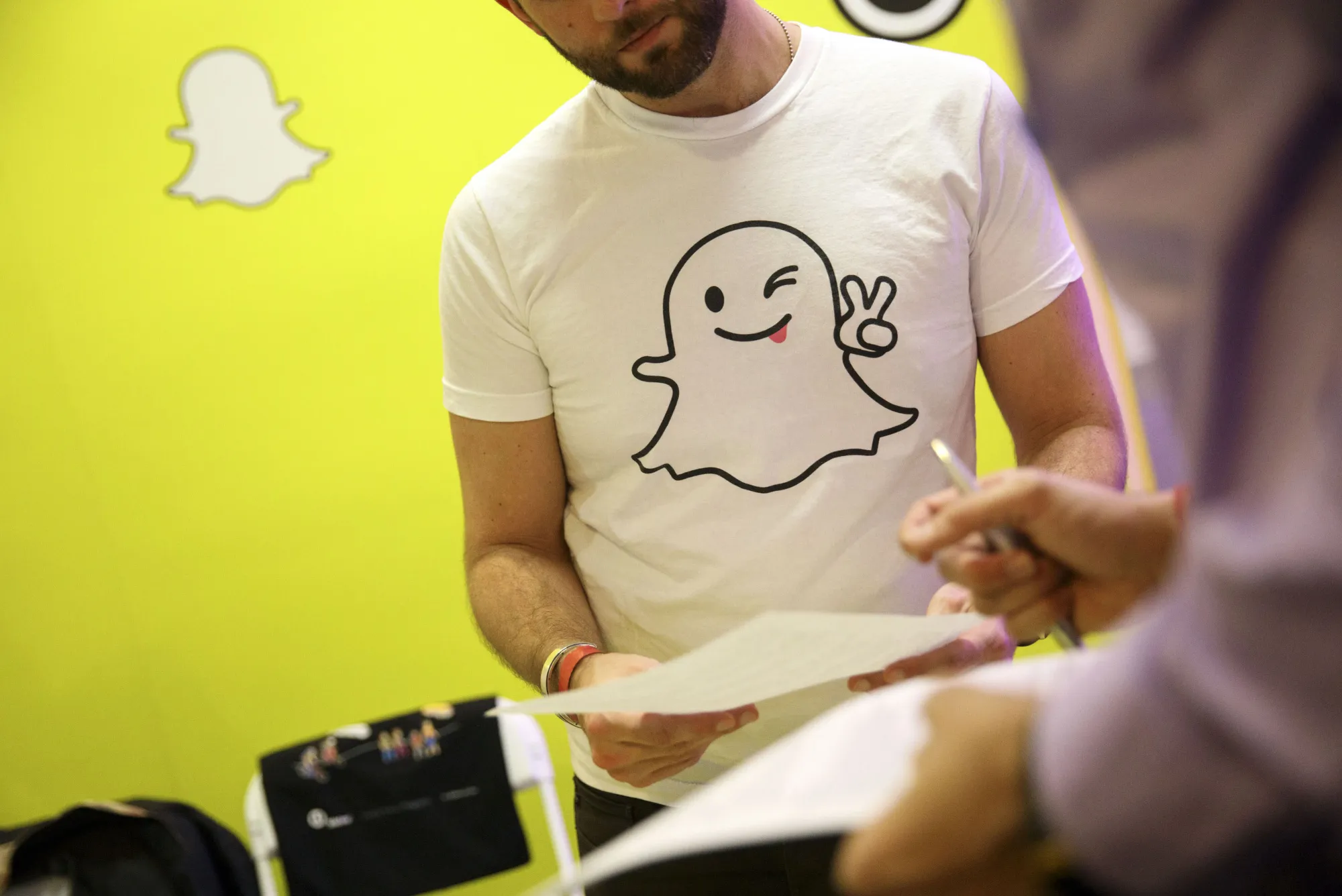 A Snap Inc. representative wears a Snapchat shirt while reviewing a resume during the TechFair LA job fair in Los Angeles.