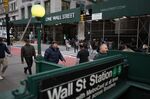 Pedestrians walk along Broadway near the New York Stock Exchange.