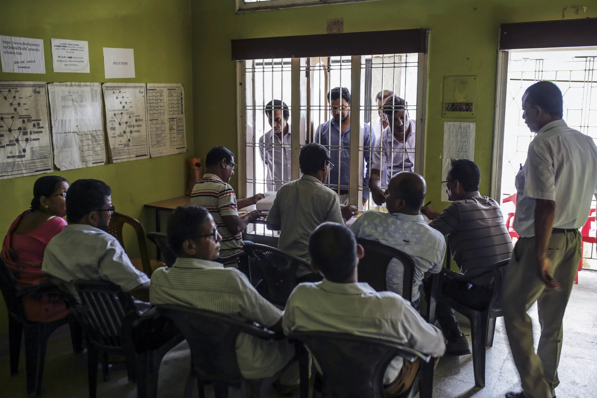 People wait at a window as officials check for their names on the National Register of Citizens at a government office in Guwahati, Assam.