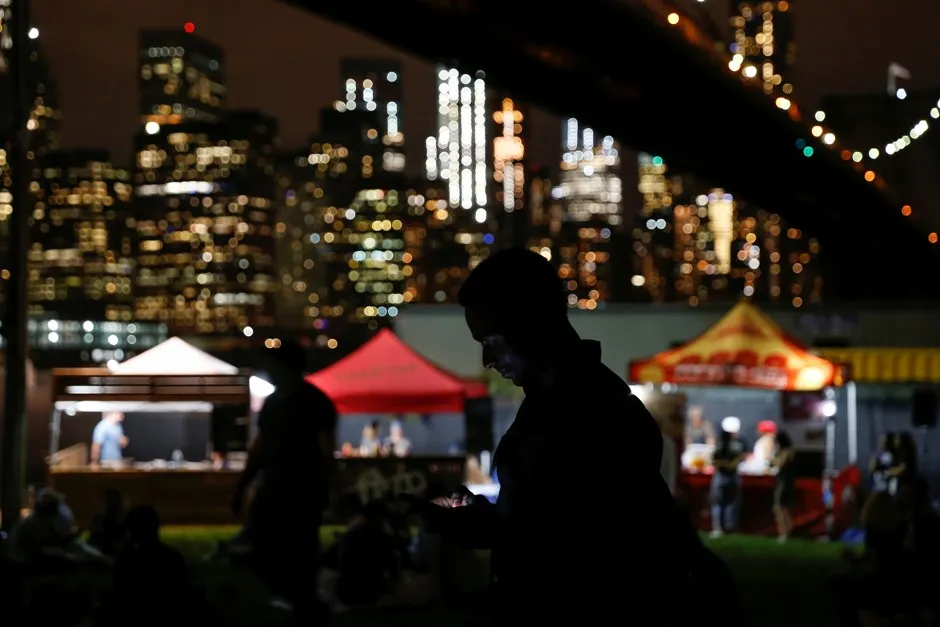 A man uses his mobile phone near food stalls at a festival in New York.