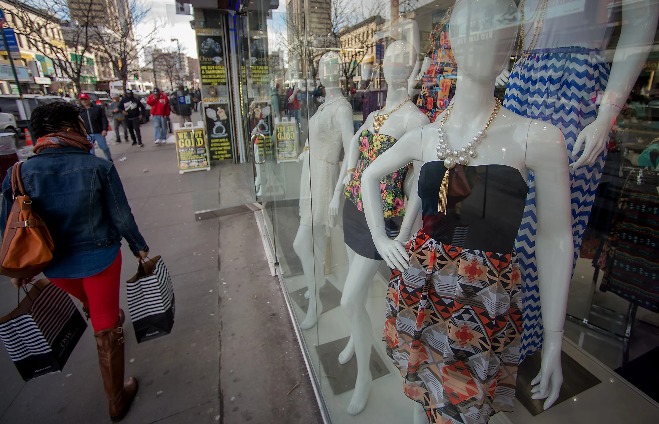 Pedestrians walk past the display window of a store in the Harlem neighborhood of New York.
