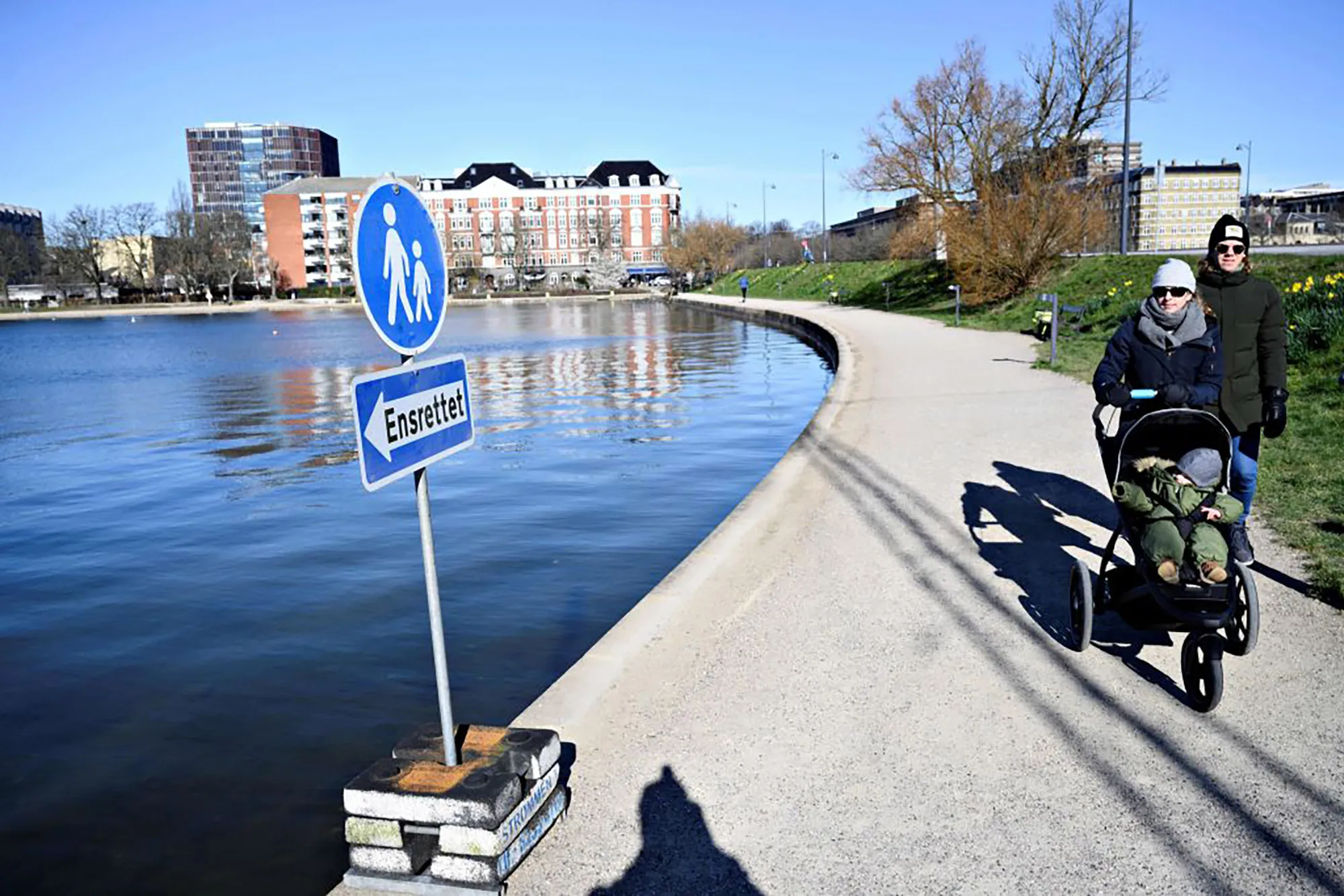 A&nbsp;couple pass&nbsp;a sign directing pedestrians to move one way only around a string of artificial lakes in Copenhagen, Denmark.