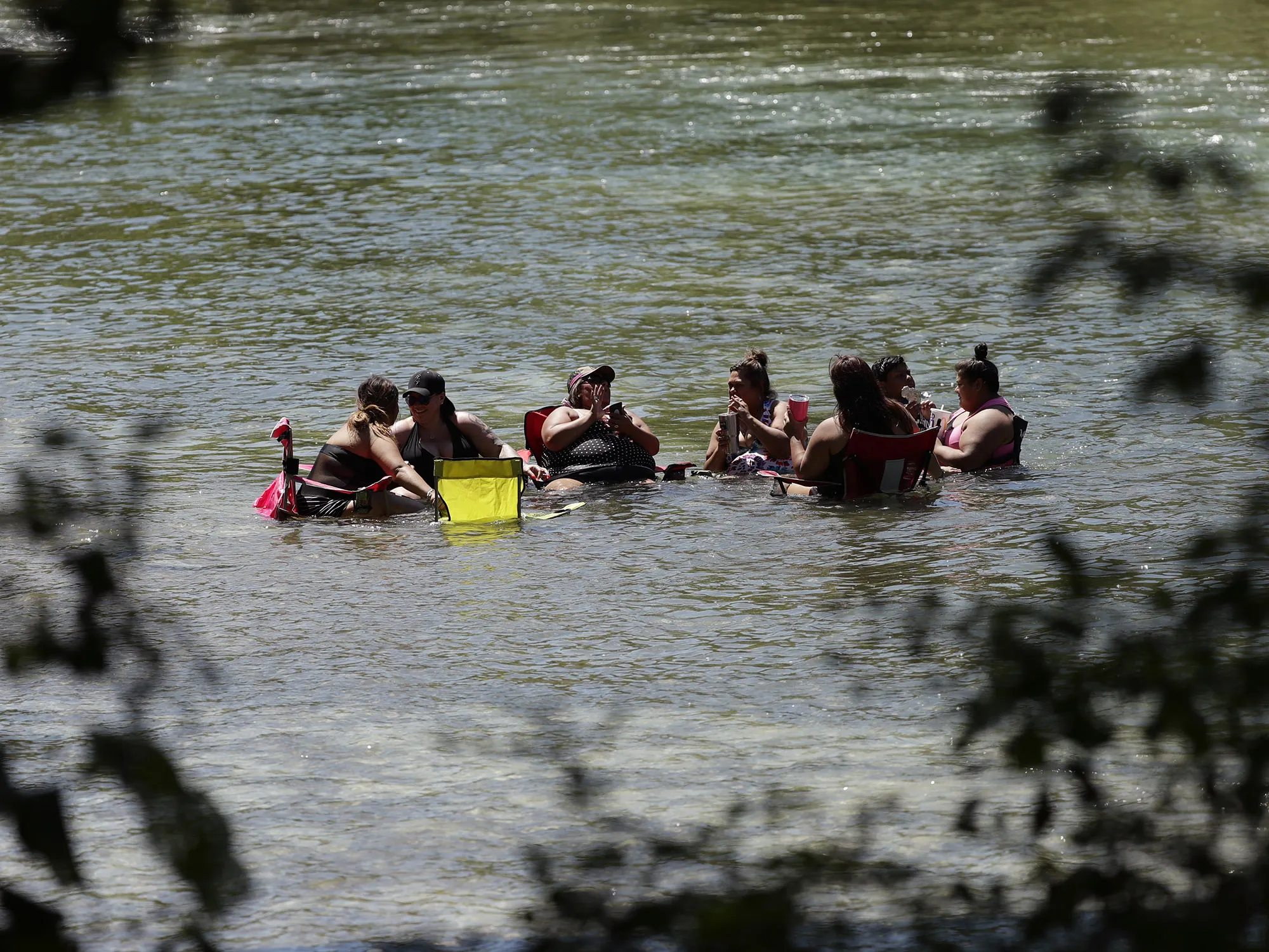 Beating the heat, a group sits in the Guadalupe River in New Braunfels, Texas.