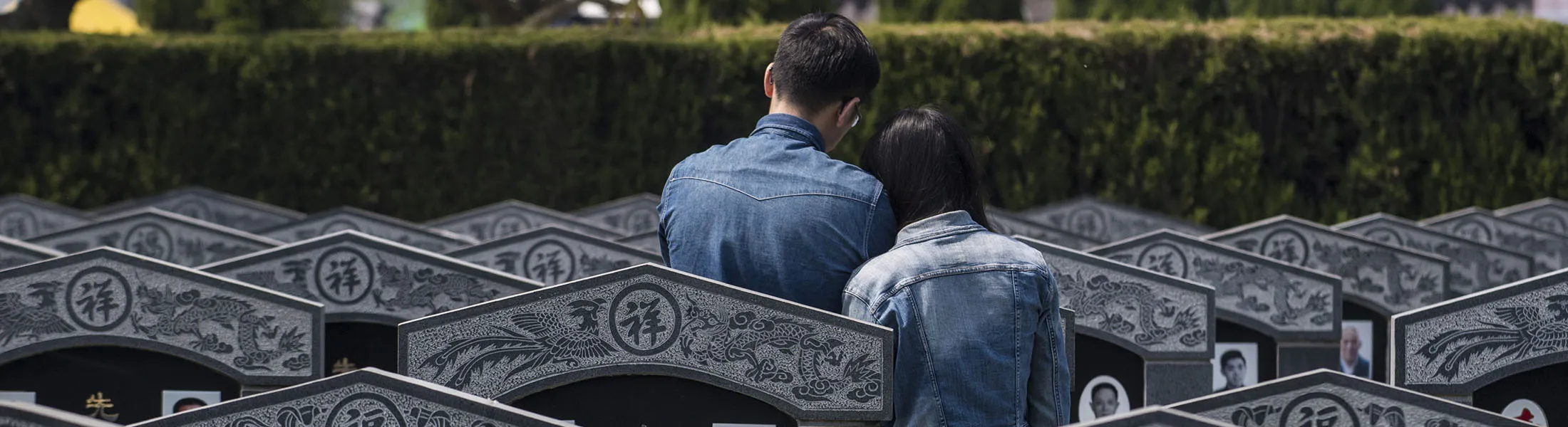 A couple pays their respect in front of a grave.