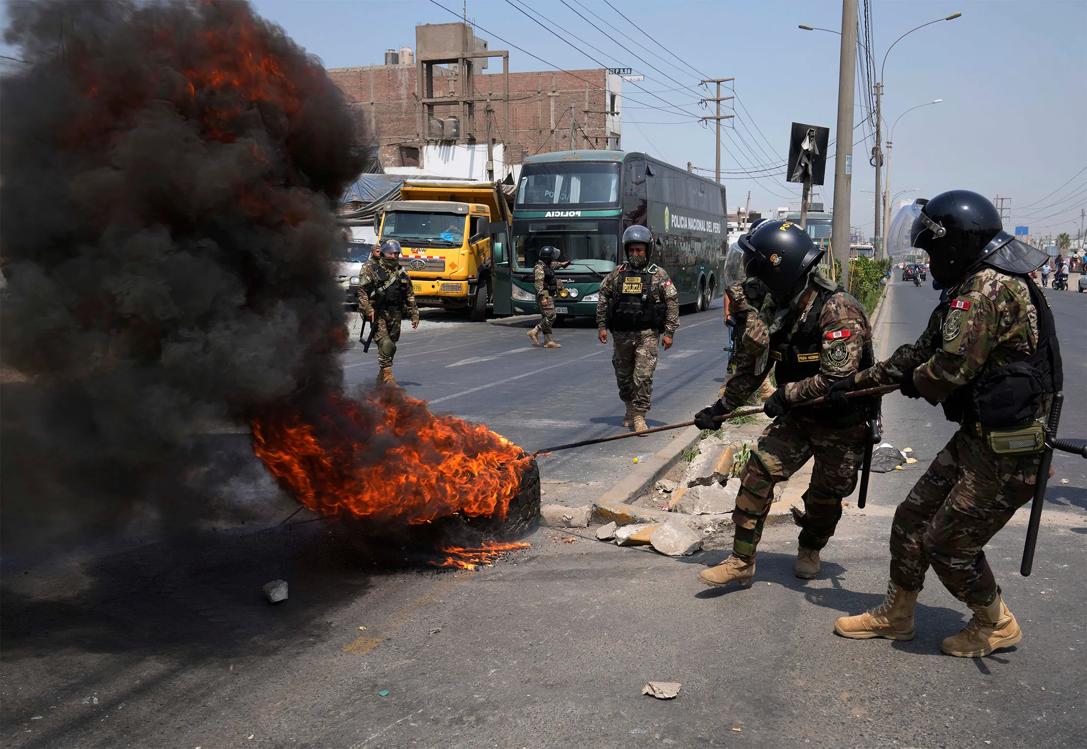 Police remove burning tires from the Central Highway where trucks and buses are parked to block the road in Huaycan, on the outskirts of Lima, on April 4. 