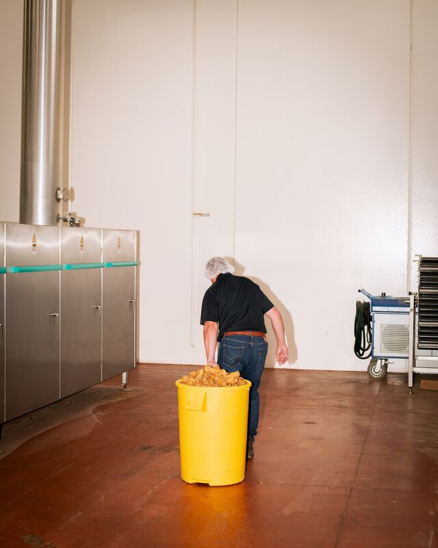 An employee drags a bucket of discarded cone fragments. 
