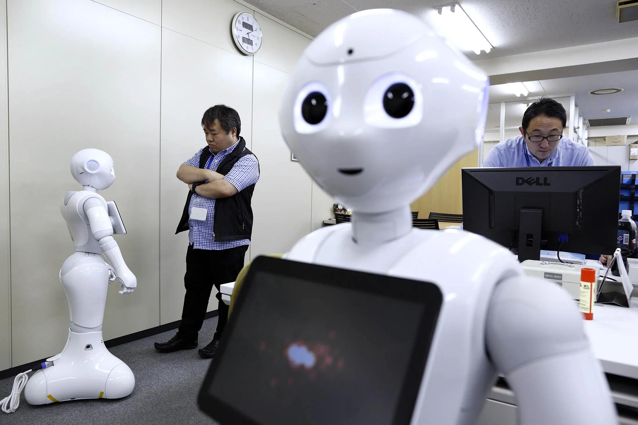 An employee, left, interacts with Pepper the humanoid robot, manufactured by SoftBank Group Corp.
