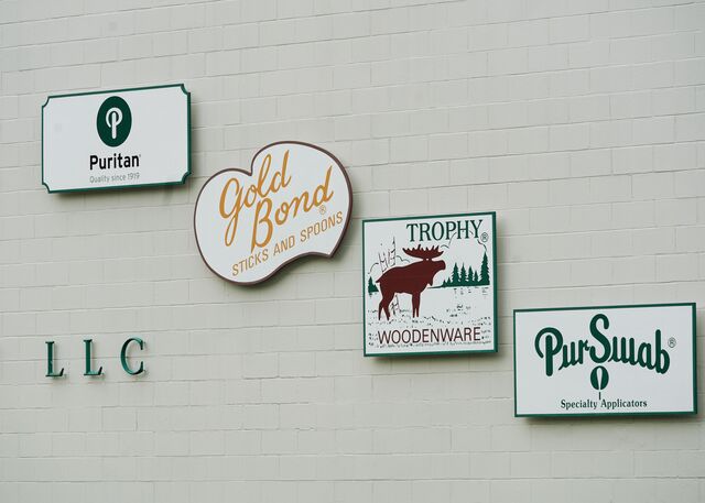 Signs bearing the names of Puritan's businesses hang on a wall in the factory.