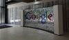 A visitor passes a sign featuring Google Inc.'s logo inside their U.K. headquarters at Six St Pancras Square in London.