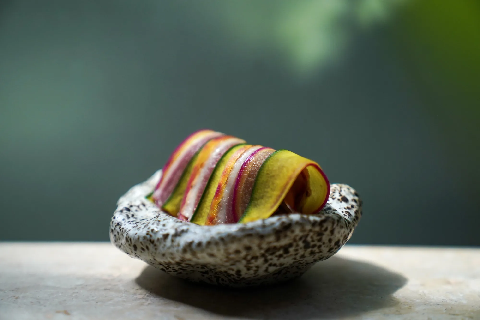 One of the dishes featured in Central's "Andean Forest" course contains colorful layered items rolled together and placed on top of a small spotted bowl. 