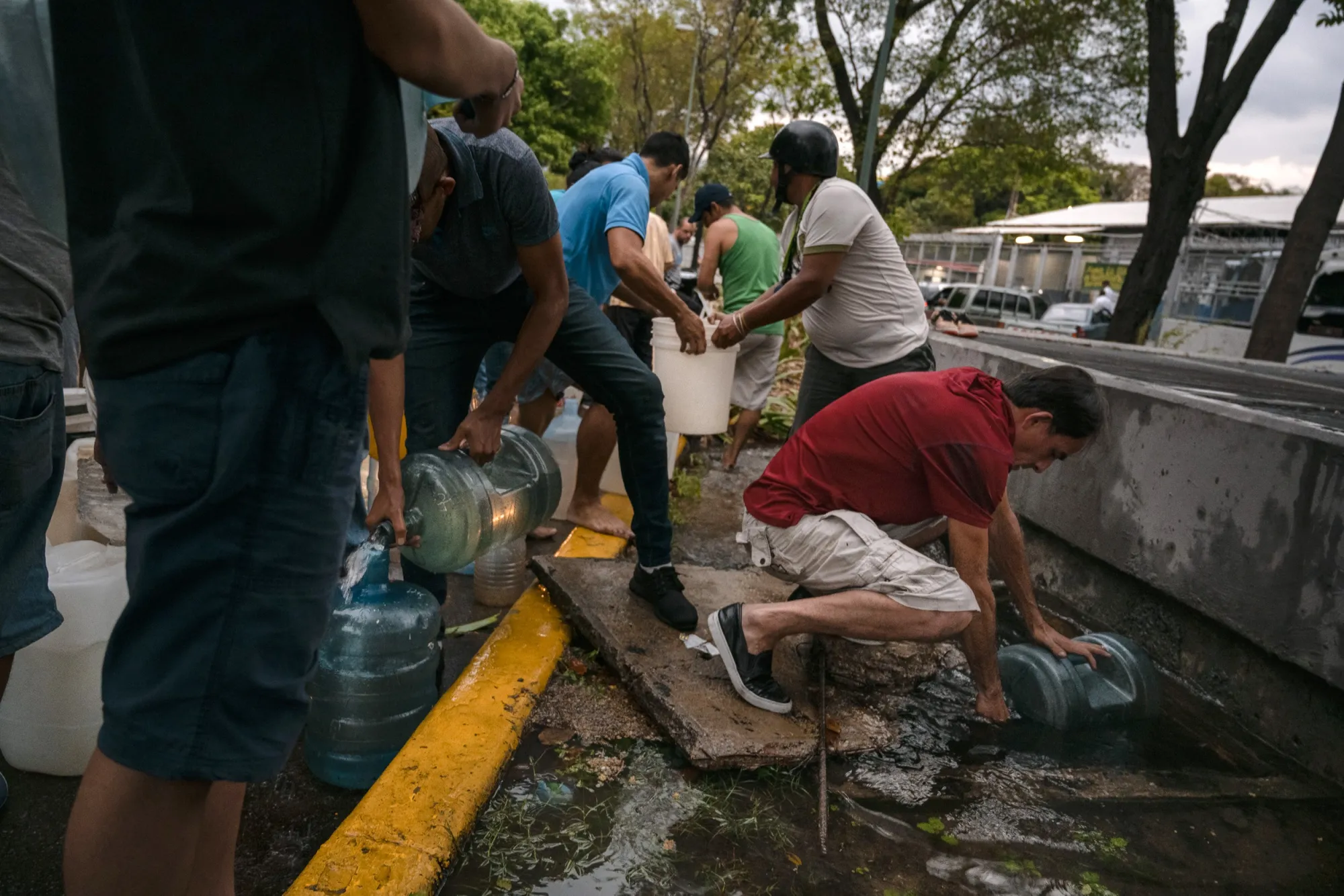 People fill containers with water from a broken pipe in Caracas on March 12.