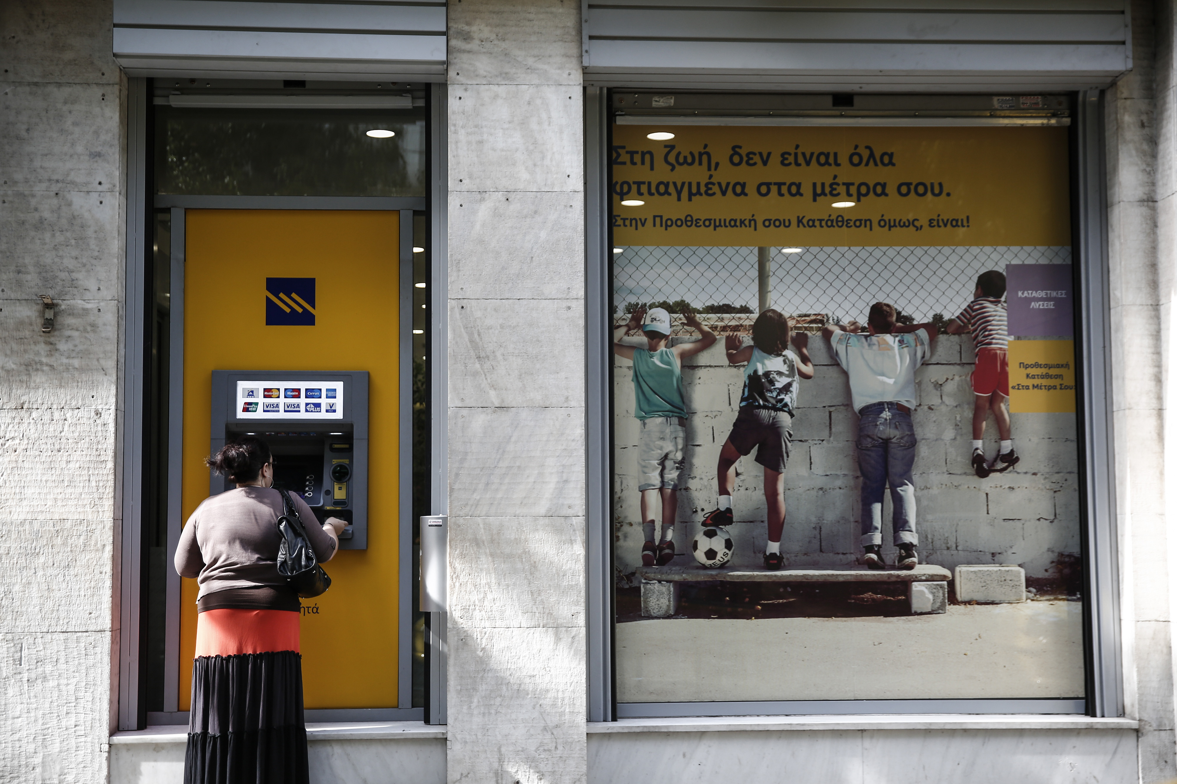 A customer uses an ATM outside a Piraeus bank branch in Athens.