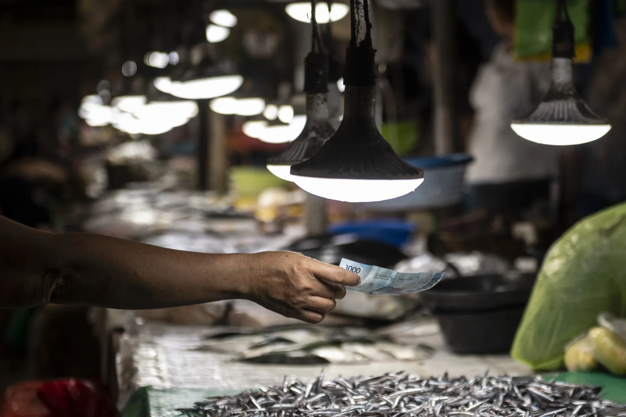 A customer hands over a one thousand Philippine peso banknote at the Mandaue City Public Market in Cebu.