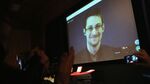 Audience members applaud as former National Security Agency (NSA) contractor turned whistleblower Edward Snowden is seen on a video conference screen during an award ceremony for the Carl von Ossietzky journalism prize on December 14, 2014 in Berlin, Germany.
