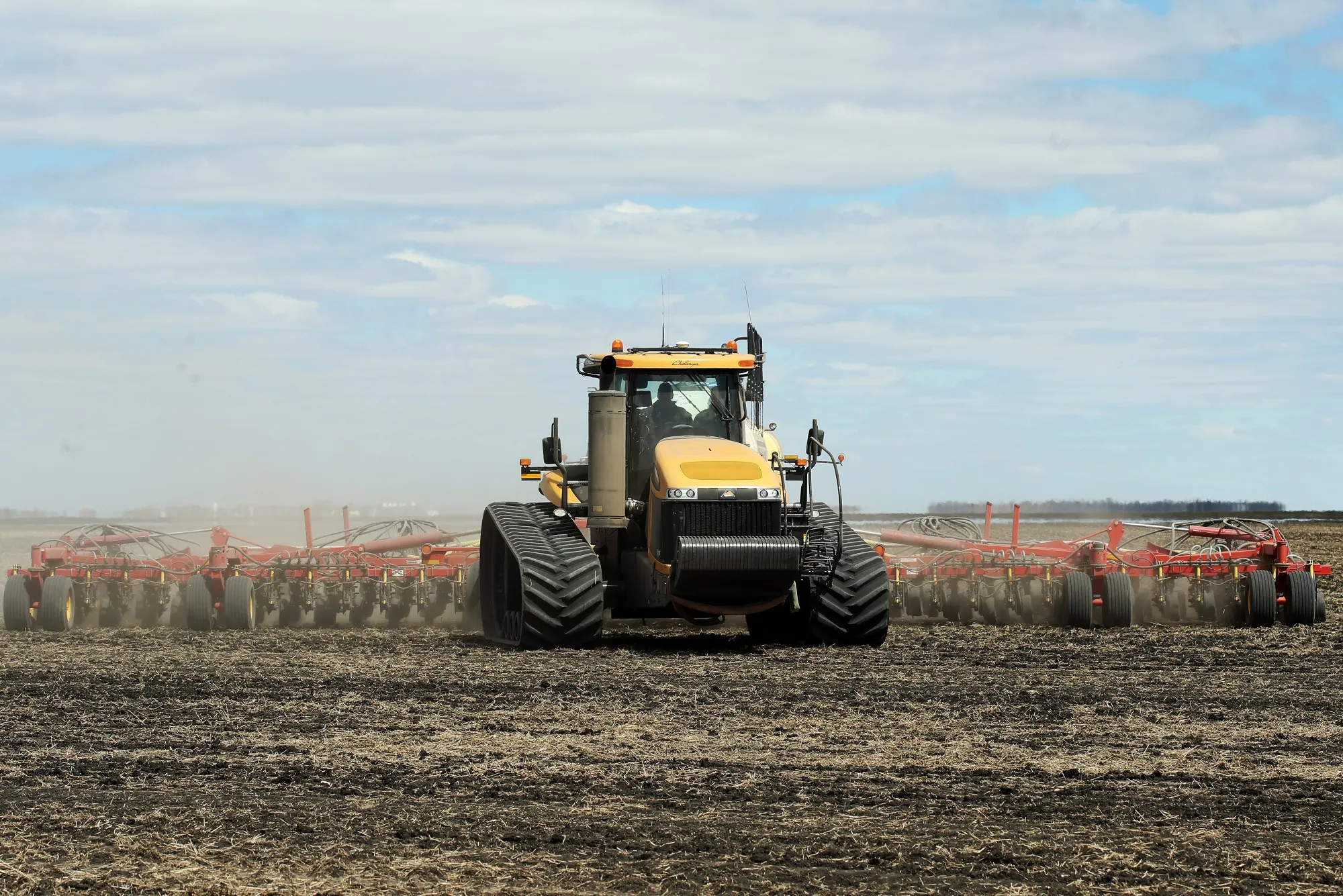 An AGCO Challenger tractor pulls a Bourgault Tillage Tools air seeder while planting canola seed.