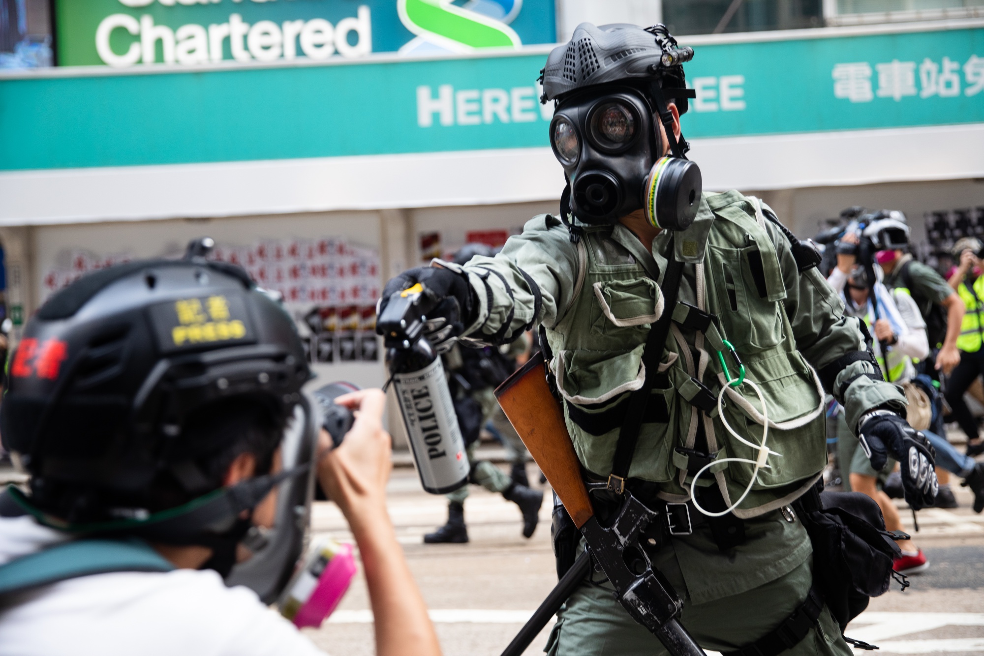 A riot police officer aims pepper spray at a journalist during a protest in Sept. 2019.