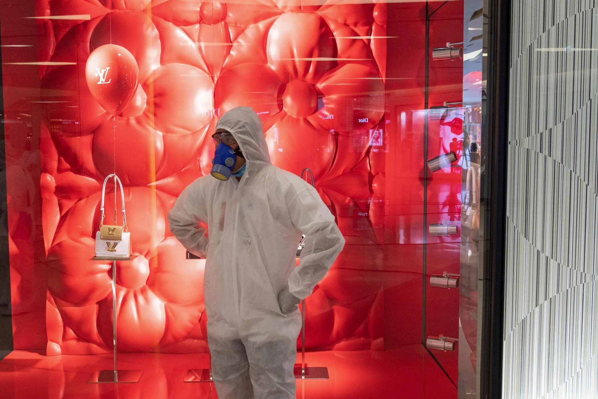 A member of a disinfecting crew stands in front of a closed Louis Vuitton store at Siam Paragon shopping mall in Bangkok.