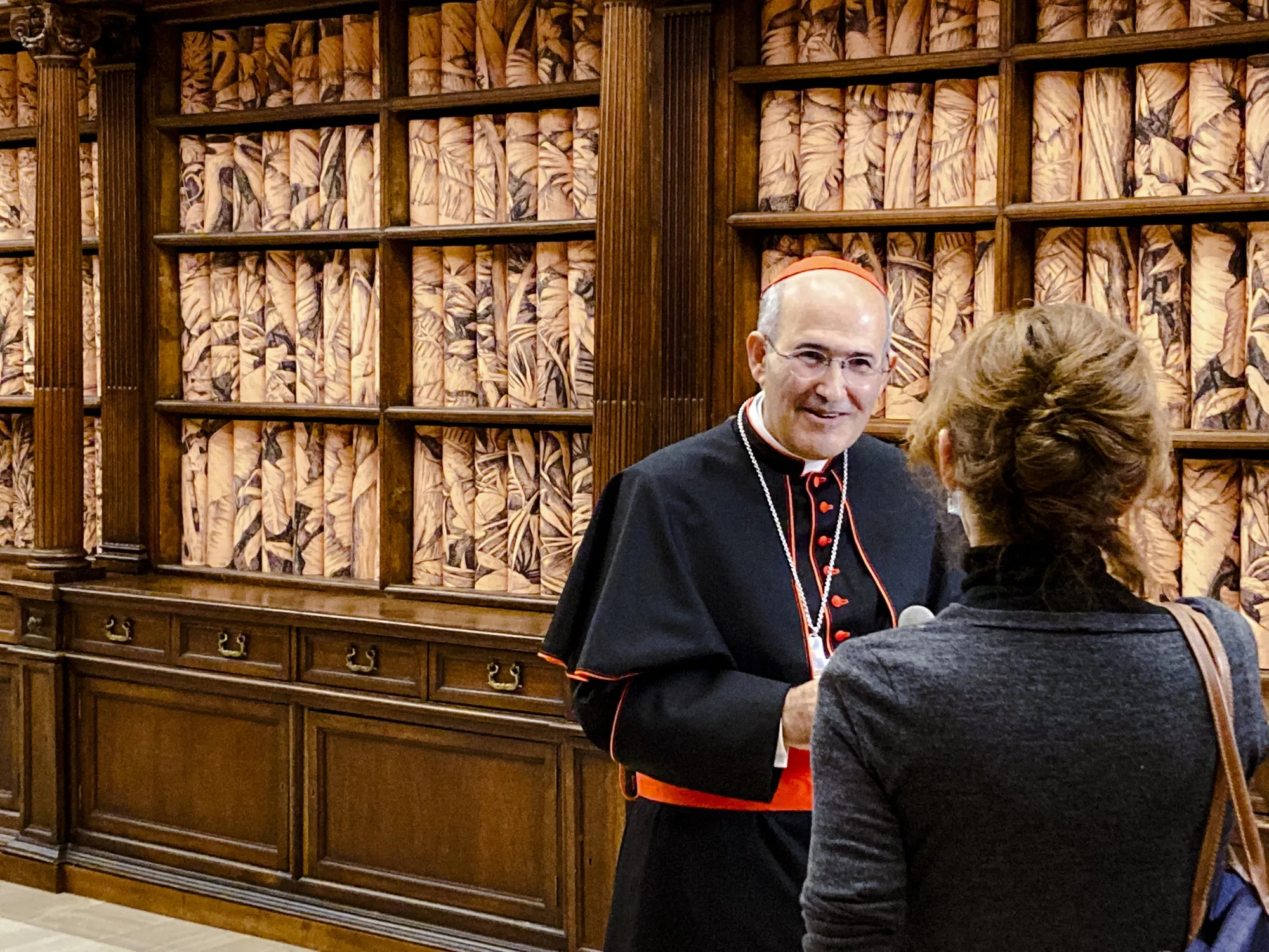 The Vatican Apostolic Librarian, Cardinal José Tolentino de Mendonça, left, speaks to a journalist, Monday, Nov. 8, 202, during the presentation to the media of the exhibition "Tutti" (All) inside the Apostolic Library. The exhibition runs through Feb. 22, 2022 and takes its inspiration from Pope Francis' 2020 encyclical "Brothers All" which combines his appeals for environmental sustainability, greater human fraternity and a more just socio-economic order in the post-COVID world. (AP Photo/Nicole Winfield)