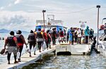 Migrants, mostly from Venezuela, get on a boat in the Colombian port town of Necocli, to cross into neighboring Panama to continue their journey towards the United States, on Oct. 11, 2022.