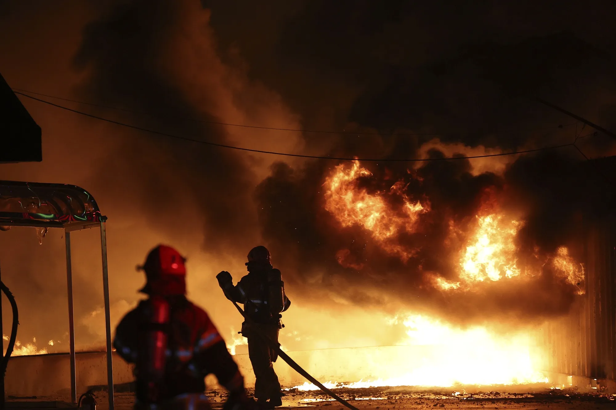 Firefighters extinguish a fire at a factory building that has been engulfed in a wildfire in Uiseong on March 22.