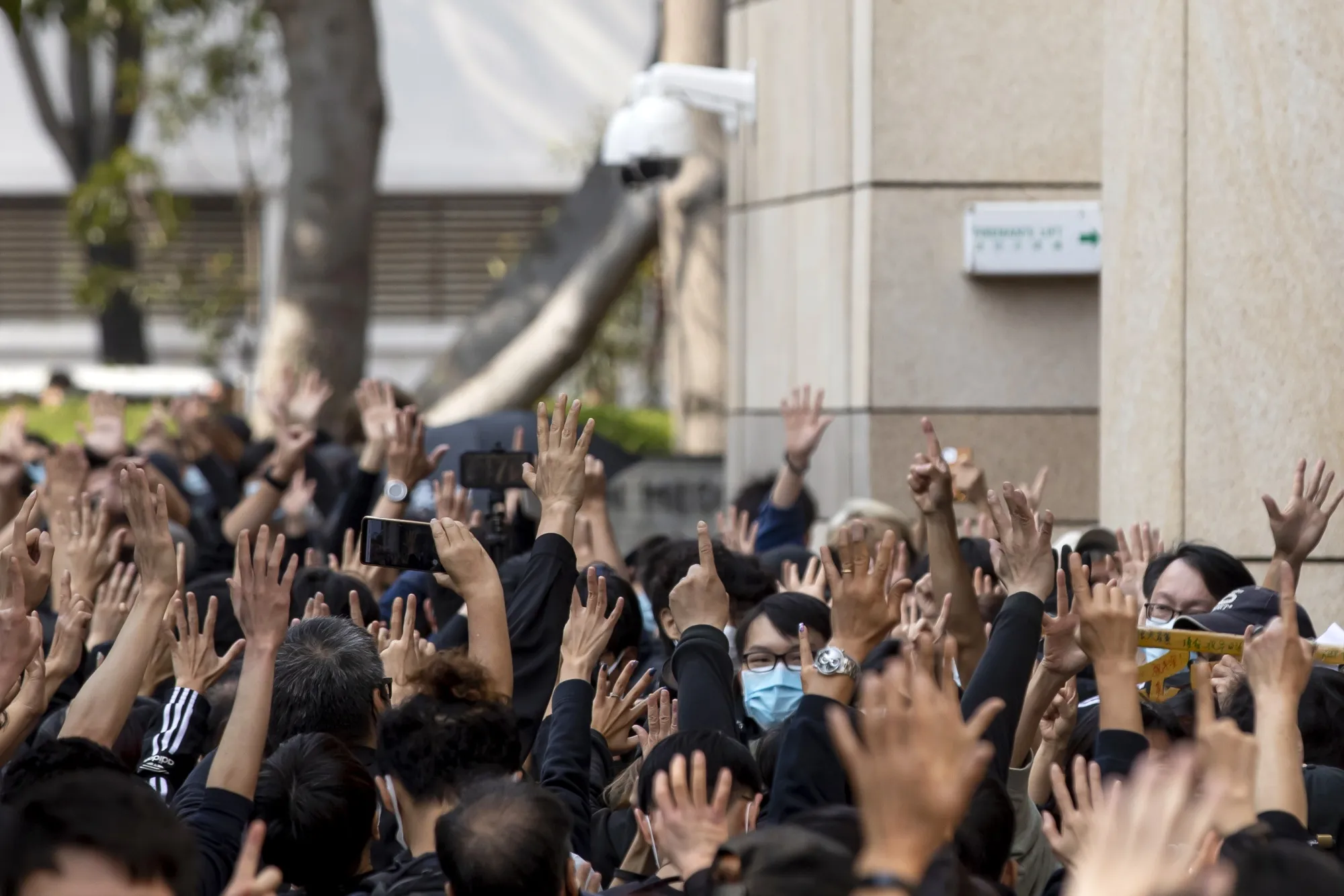 Pro-democracy demonstrators gesture the “Five demands, not one less” protest motto while waiting to enter the West Kowloon Magistrates’ Courts in Hong Kong on March 1.