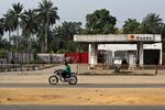 A man rides a motorcycle past a closed Oando Plc gas station in Port Harcourt, Nigeria.