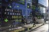 An electronic stock board reflects pedestrians outside a securities firm in Tokyo.