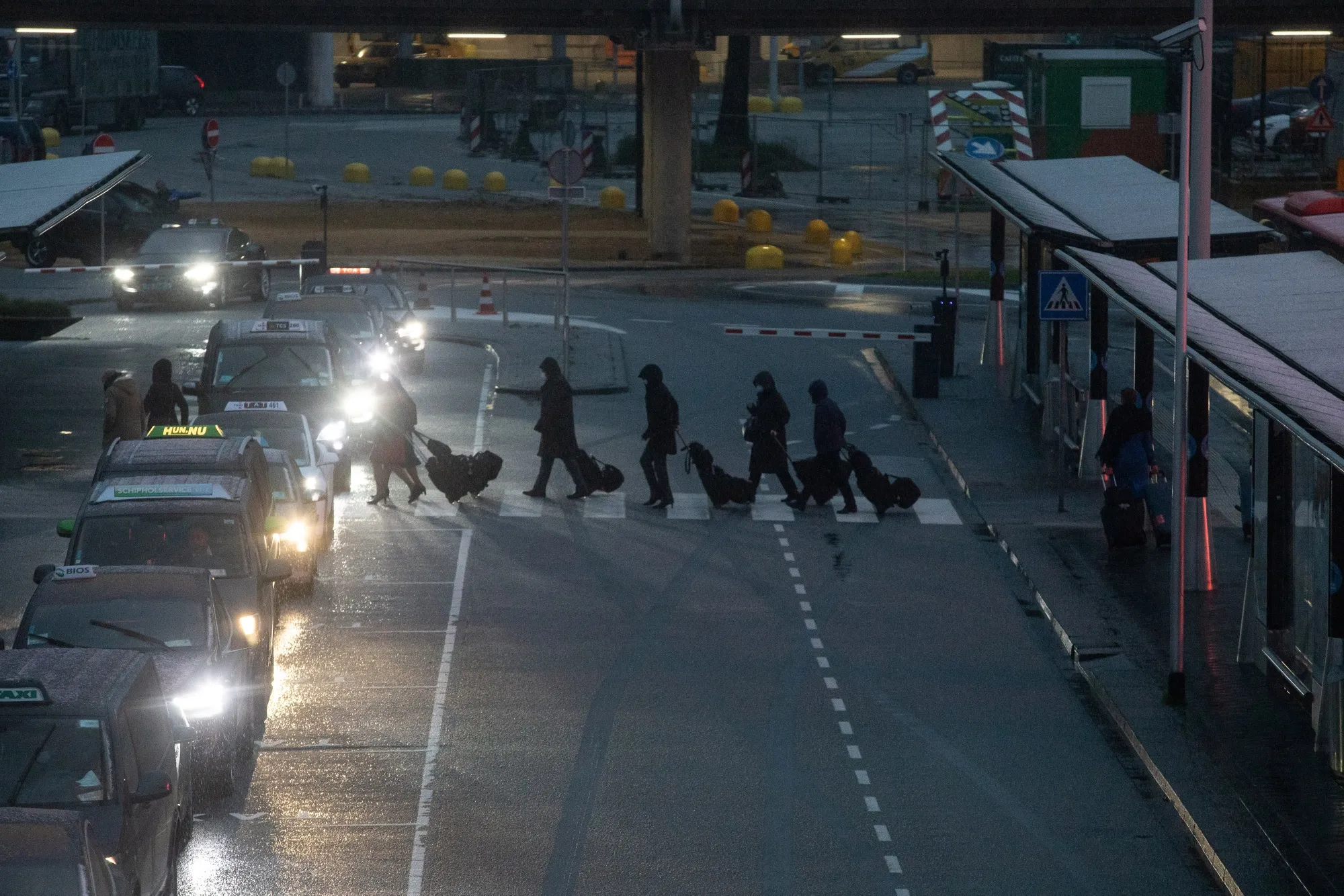 Travelers wheel luggage by a taxi set down area outside Schiphol Airport in Amsterdam.