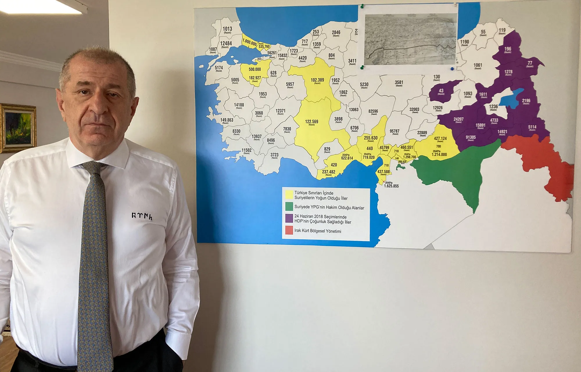 Umit Ozdag in his Ankara office, alongside a map showing refugee density across Turkey.