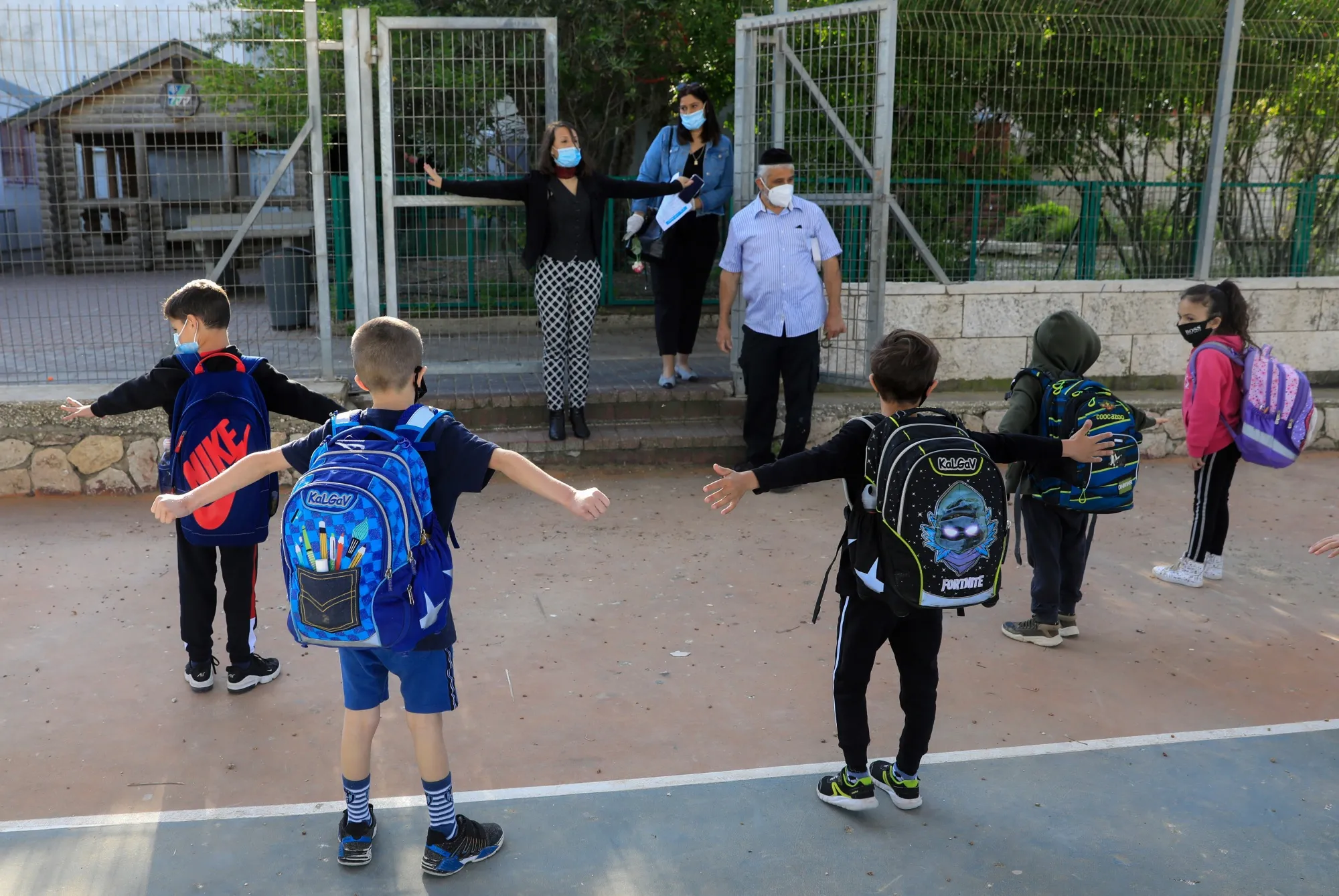 A school principal demonstrates how to maintain social distancing at an elementary school in the suburbs of Jerusalem on May 3, 2020.