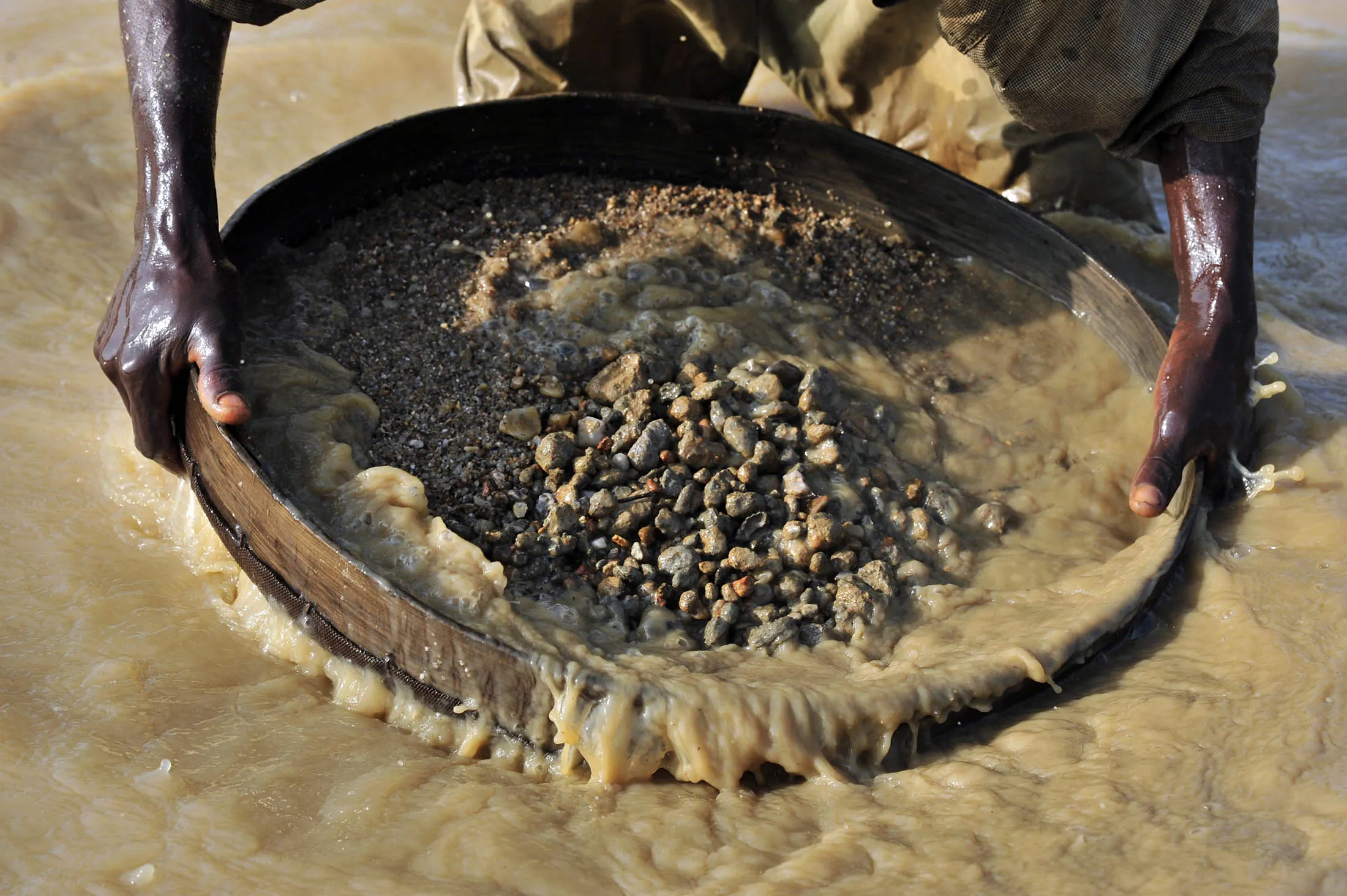 A diamond prospector filters earth from a river in Koidu, Sierra Leone.
