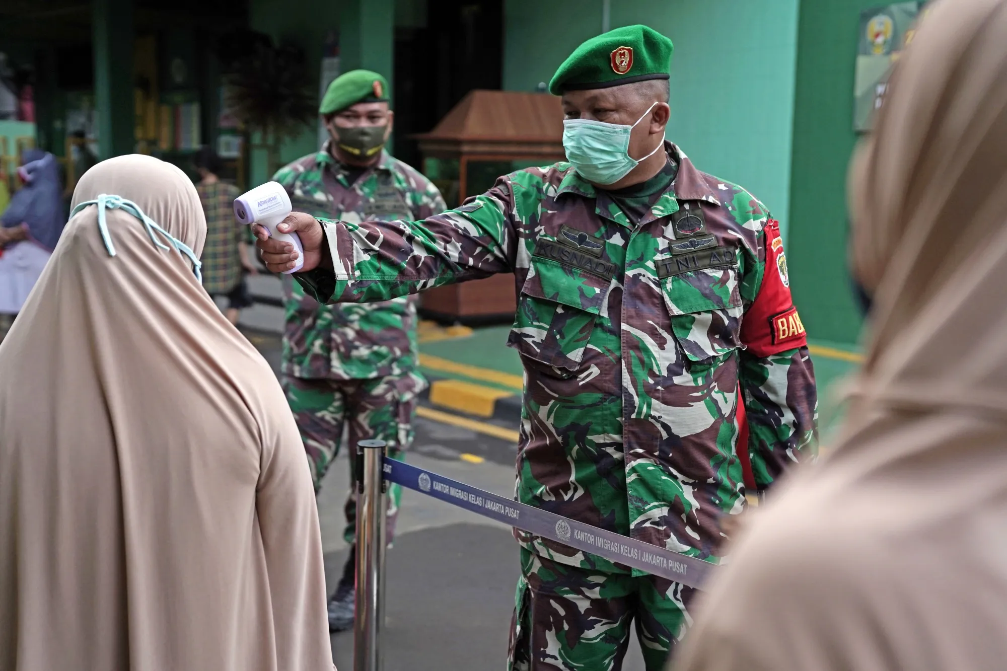 A soldier takes temperatures at a rice distribution center in Jakarta, Indonesia, on May 13, 2020.