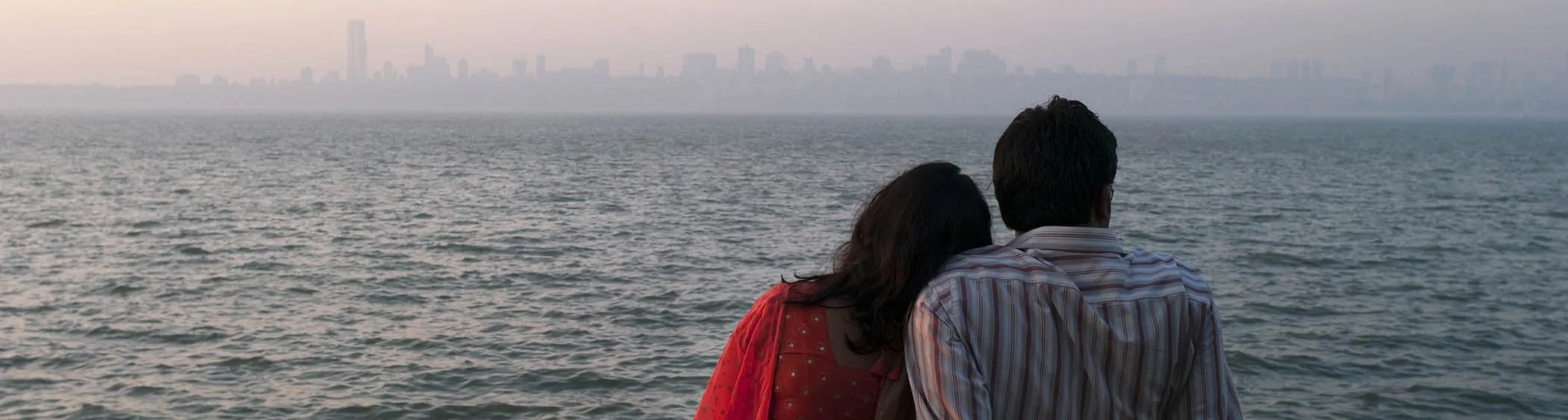 An Indian couple enjoy a sunset view from Marine Drive in Mumbai, India.
