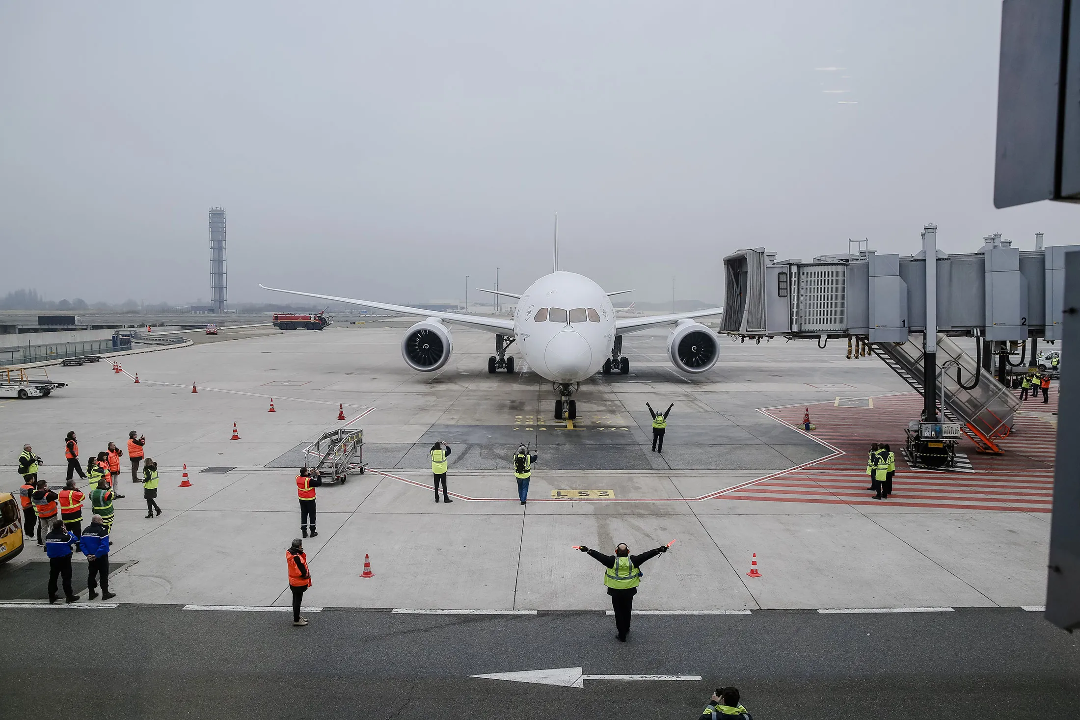 Ground staff gesture as a Boeing Inc. 787-9 Dreamliner passenger aircraft stands on the tarmac at Charles de Gaulle Airport.
