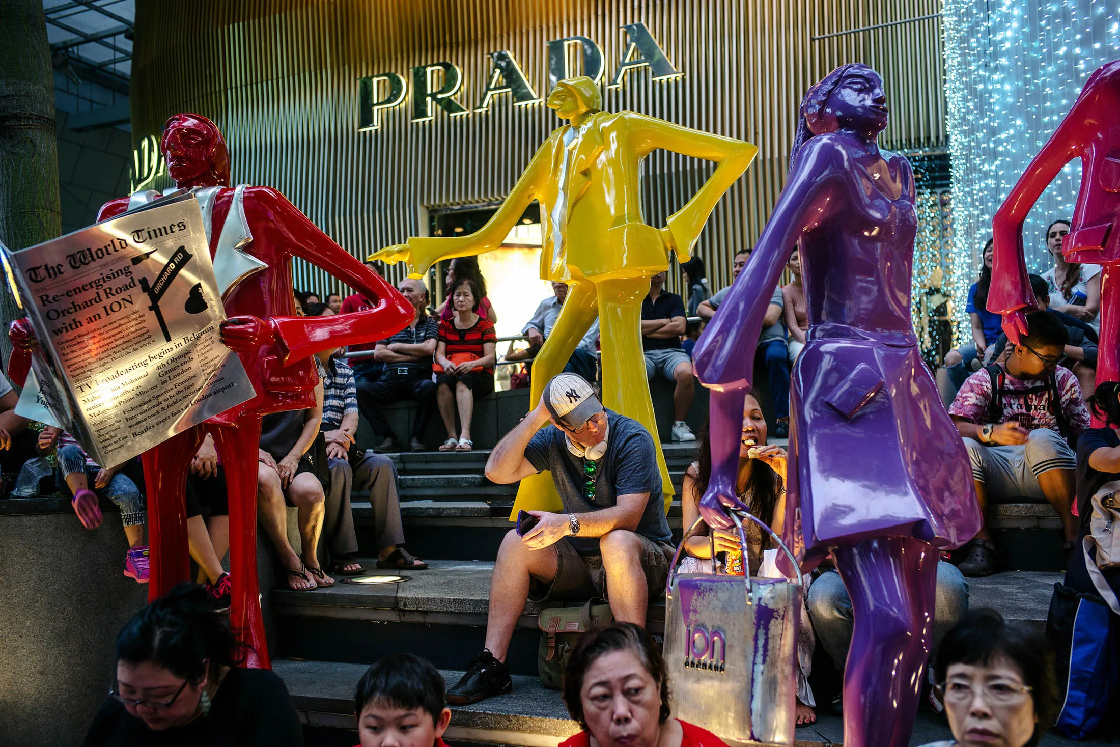 People sit next to sculptures outside a Prada SpA luxury fashion store on Orchard Road in Singapore, on Sunday, Dec. 16, 2016. Shopping has overtaken gambling as the biggest earner in Singapore's tourism industry for the first time since 2012, surging 44 percent in the six months through June from a year ago, official data show.
