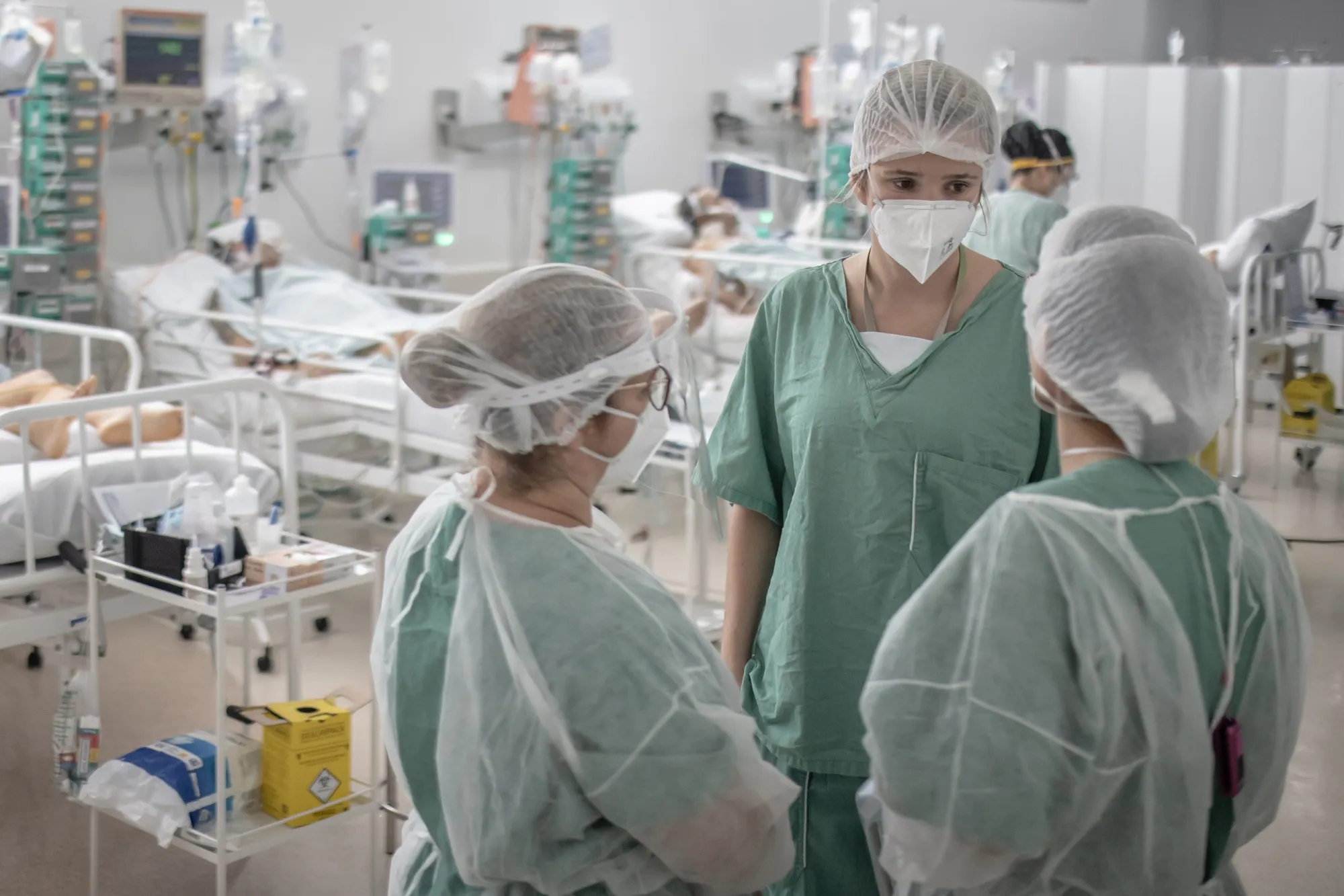Healthcare workers hold a meeting while treating patients inside a Covid-19 ICU at a field hospital in the Heliopolis favela of Sao Paulo.