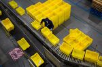 A worker stacks bins at an Amazon fulfillment center.
